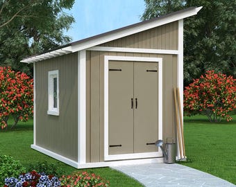 May include: A small, tan and white shed with a slanted roof, double doors, and a small window. The shed is surrounded by green grass, red flowering bushes, and a stone walkway. Gardening tools and a watering can are placed next to the shed.