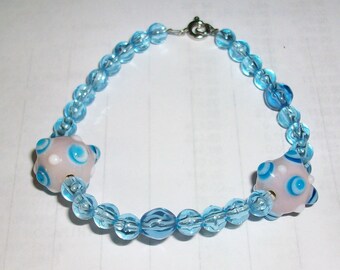 pink with bump glass bead bracelet with small blue beads measures 8 inches