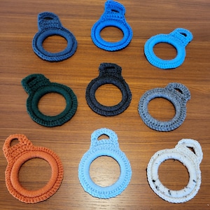 May include: Ten crocheted rings in various colors, including blue, green, orange, and white. The rings are all about the same size and have a loop at the top.