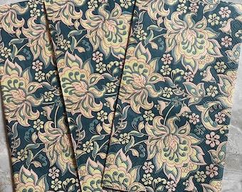 May include: Three teal blue napkins with a floral pattern in shades of yellow, pink, and green. The pattern is intricate and features paisley-like designs.
