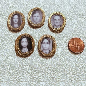 May include: Five miniature oval portraits with gold-colored frames, each featuring a black and white image of a person. A penny is next to the portraits for size comparison. The portraits are arranged on a patterned surface.