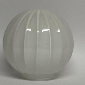 May include: A spherical, white glass lampshade featuring vertical ribbed detailing. The shade has a glossy finish and is designed for use with various lighting fixtures. The design is simple and elegant, suitable for any room.