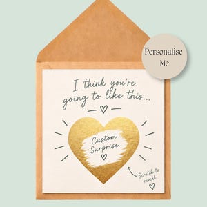 May include: A square white greeting card inside a brown kraft paper envelope. The card features the text I think you're going to like this, a gold foil heart with the text Custom Surprise, and the text Scratch to reveal with a small arrow.