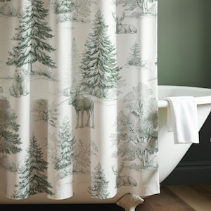 May include: A forest-themed shower curtain with a white background and a green and gray illustration of trees, deer, and other wildlife. The curtain is hanging in front of a white bathtub. A small wooden stool holds towels and a soap dispenser.