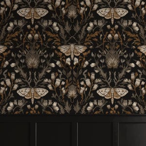 Op de afbeelding: Donker behang met een herhalend patroon van motten en bloemelementen in bruin, beige en grijs tegen een zwarte achtergrond. Het ontwerp bevat gestileerde motten en botanische illustraties, wat een vintage esthetiek creëert. Het onderste gedeelte toont een zwart paneel.