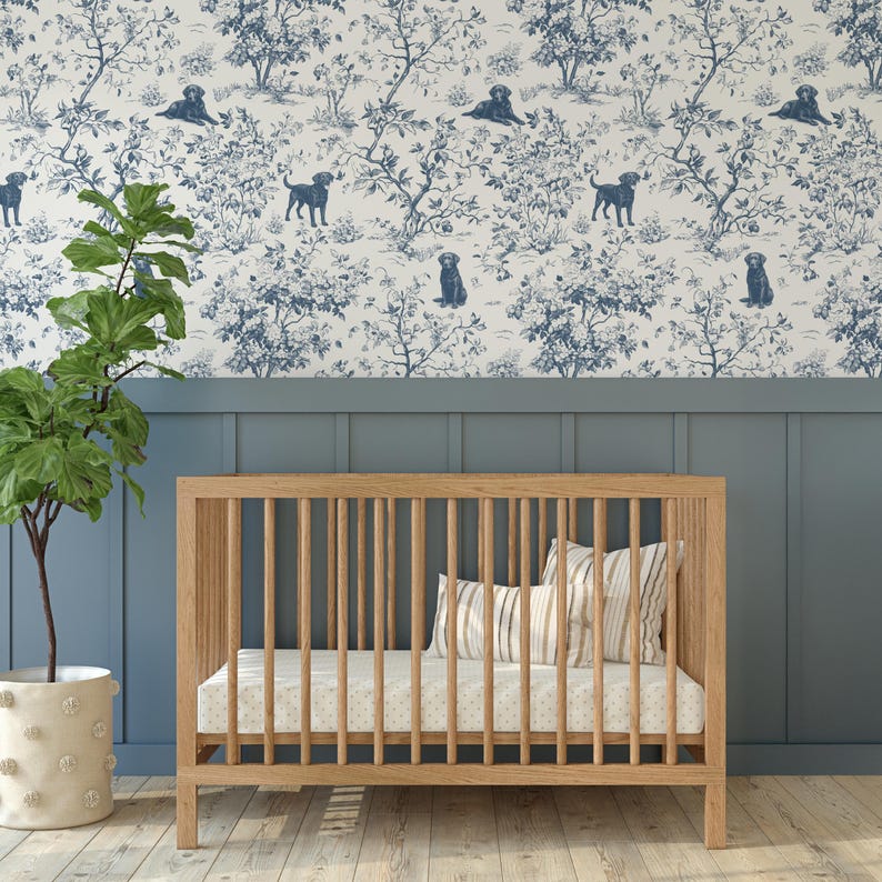 May include: A wooden crib with vertical slats, a mattress, and pillows. The crib is set against a blue wall and a wallpaper with a blue and white dog and tree pattern. A potted plant is on the left.