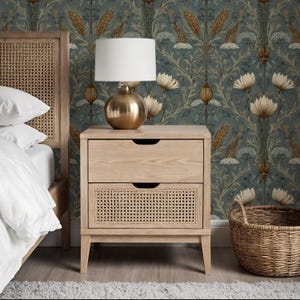 May include: A light wood nightstand featuring two drawers, with the top drawer having a smooth front and the bottom drawer showcasing a woven cane panel. The nightstand stands on four tapered legs and is topped with a brass lamp with a white shade.