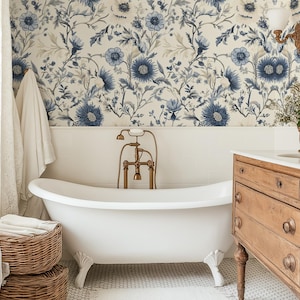 May include: A white clawfoot bath with gold fixtures in a bathroom featuring floral wallpaper with blue and white flowers. The bathroom also has a wooden vanity with drawers and a white porcelain sink.