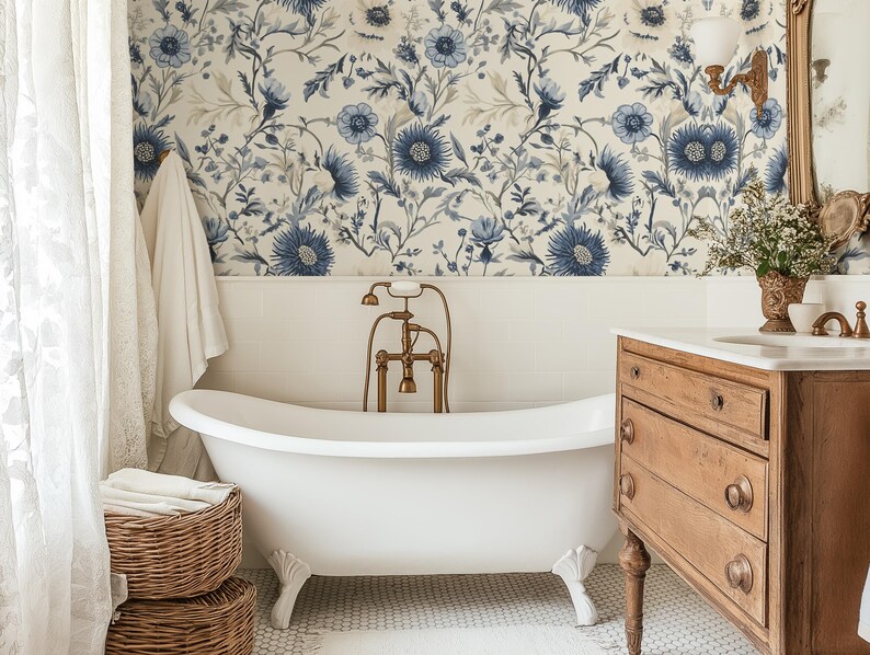 May include: A white clawfoot bath with gold fixtures in a bathroom featuring floral wallpaper with blue and white flowers. The bathroom also has a wooden vanity with drawers and a white porcelain sink.