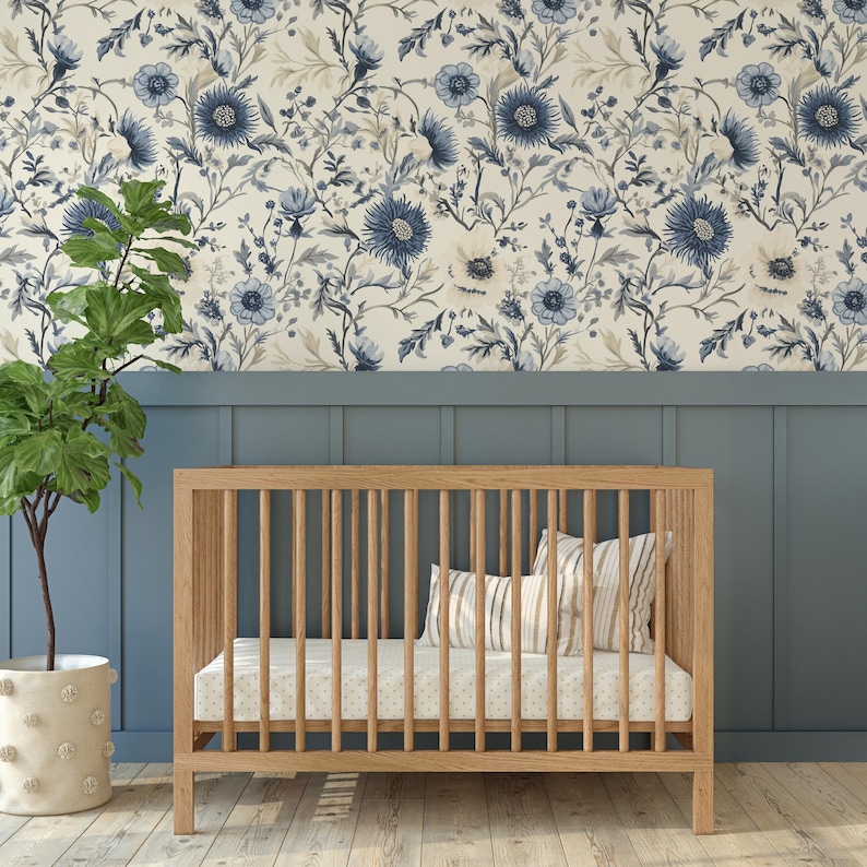 May include: A wooden cot with a white and blue floral patterned wallpaper behind it. The cot has a white mattress and a striped pillow.