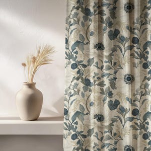May include: A curtain featuring a botanical pattern of large white flowers, dark blue circular seed heads, and muted green foliage on a cream background, positioned next to a beige ceramic vase containing dried wheat stalks.