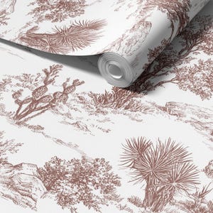 Könnte beinhalten: Eine Tapetenrolle mit einem Wüstenlandschaftsdesign in Braun und Weiß. Das Muster zeigt Illustrationen von Kakteen, Bäumen und felsigem Gelände und erzeugt eine Vintage-Toile-Ästhetik. Das Papier ist teilweise abgerollt.