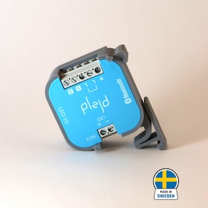 Può includere: Un dispositivo per la casa intelligente blu e grigio con il testo "plajd" e "Bluetooth" su di esso. Il dispositivo ha un'etichetta che dice "LED-10" e "SELV".