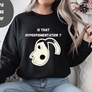 May include: A black sweatshirt with the text "IS THAT HYPERPIGMENTATION?" and a cartoon drawing of a face with a black dot on the cheek.