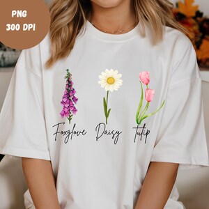 May include: White t-shirt with a graphic of three flowers: a pink foxglove, a white daisy, and a pink tulip. The flowers are labeled "Foxglove", "Daisy", and "Tulip".
