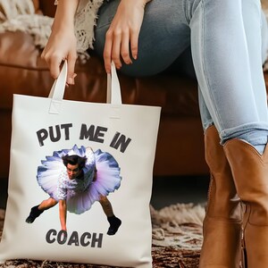 May include: White tote bag with a black and white graphic of a person in a tutu with the text "Put me in coach".