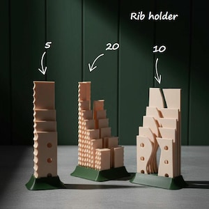 May include: Three beige rib holders with green bases are shown against a dark green backdrop. The holders are labelled with the numbers 5, 20, and 10, and have different textures and shapes.