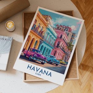 Puede incluir: Una colorida impresión artística de La Habana, Cuba, con coches antiguos en una calle bordeada de edificios vibrantes en tonos rosa, azul y amarillo. La palabra "HAVANA" está impresa en azul, con "CUBA" debajo.