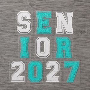 May include: A set of individual iron-on letters and numbers spelling out SENIOR 2027. The characters feature a varsity-style block font with a glittery texture, alternating between white and bright turquoise colors on a clear backing material.