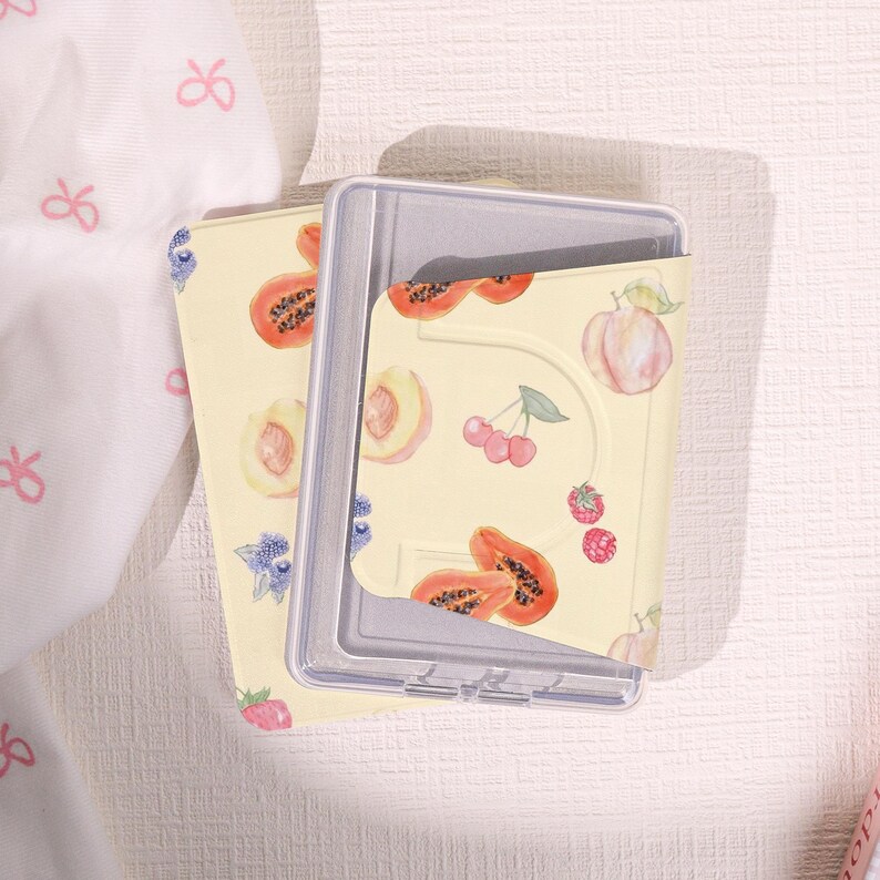 May include: A set of three ceramic mugs with a speckled, cream-colored glaze. Each mug features a different hand-painted design: a blue and green leaf, a yellow flower, and a red berry. The mugs have a simple, rounded shape.