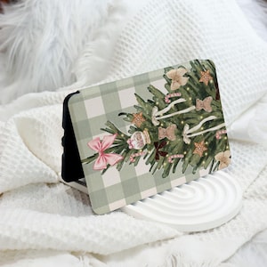 May include: A green and white gingham phone case featuring a Christmas tree design. The tree is decorated with pink bows, candy canes, and baubles.