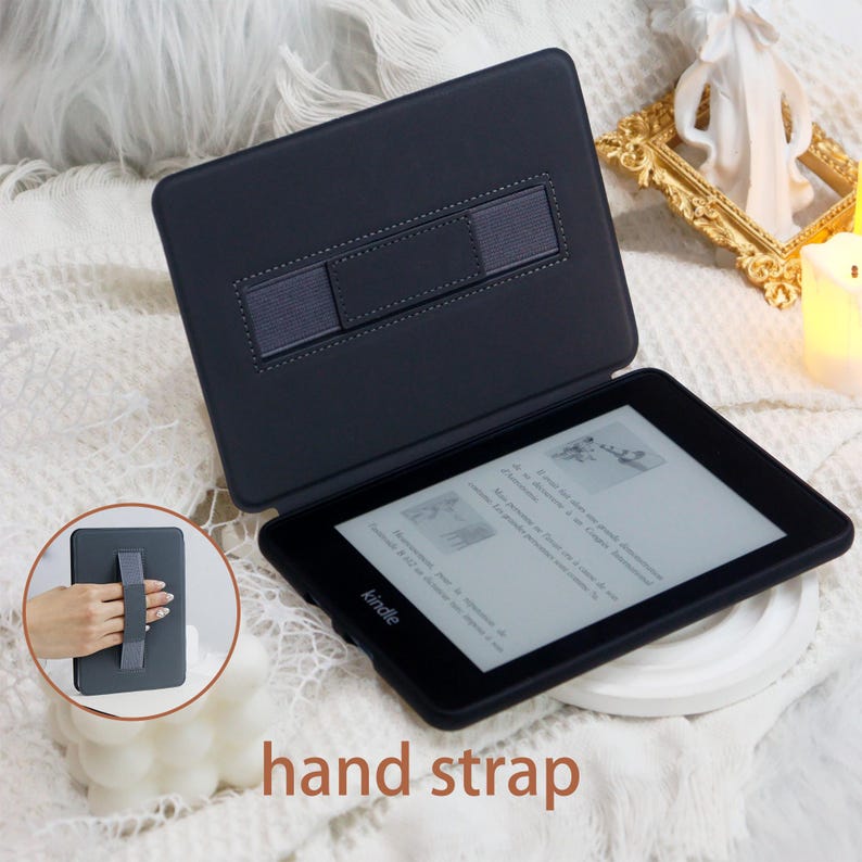 May include: Black Kindle e-reader case with a hand strap. The case has a built-in hand strap for easy carrying. The Kindle is open and displaying a page of text.