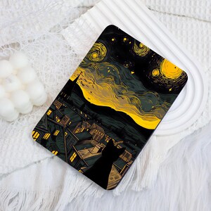 May include: A rectangular tablet case featuring a graphic illustration of a black cat silhouette overlooking a town at night. The scene includes a swirling yellow sky with stars, dark rooftops with glowing yellow windows, and a dark landscape.