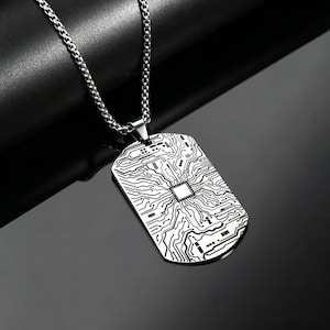 May include: A silver-toned dog tag pendant necklace featuring a detailed black engraved circuit board pattern. The rectangular pendant hangs from a matching silver-colored box chain, showcasing a central square motif with intricate lines.