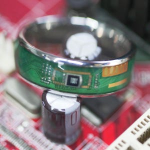 May include: A silver ring with a green circuit board design. The circuit board has a gold-colored chip and a black chip with the word "TODT" printed on it.