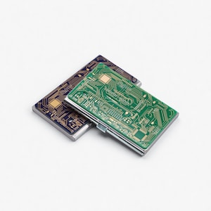 May include: Two rectangular cardholders with circuit board designs. One is green with silver trim, the other is dark blue with gold trim. The cardholders are made of metal and have a hinged closure.