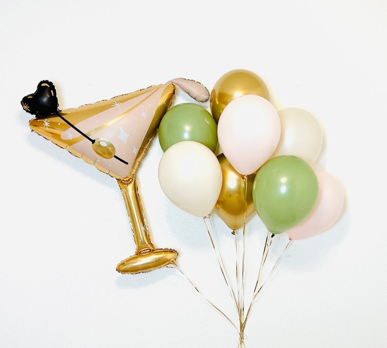 K&ouml;nnte beinhalten: Ein Set aus goldenen, gr&uuml;nen und rosafarbenen Ballons. Die Ballons sind in einer Traube angeordnet, mit einem goldenen Ballon in Form eines Martini-Glases in der Mitte.