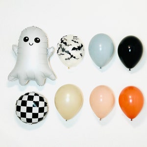 Pu&ograve; includere: Un set di decorazioni per feste di Halloween con un palloncino fantasma argentato, un palloncino a scacchi bianco e nero, un palloncino nero, un palloncino grigio chiaro, un palloncino crema, un palloncino pesca, un palloncino arancione e un palloncino trasparente con un motivo a pipistrello nero.