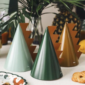May include: Four party hats with a dinosaur theme. The hats are green, brown, and light green with a brown dinosaur tail design.