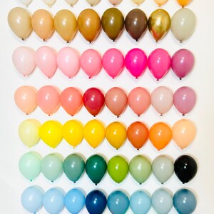 Puede incluir: Un arco&iacute;ris de colores en una colecci&oacute;n de 10 filas de 10 globos. Los globos est&aacute;n dispuestos en un degradado de blanco a morado.