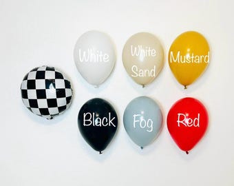 Puede incluir: Nueve globos de diferentes colores y patrones, incluyendo un damero blanco y negro, un negro, un blanco, un blanco arena, un amarillo mostaza, un gris niebla y un rojo. Los globos están etiquetados con las palabras "Blanco", "Blanco Arena", "Mostaza", "Negro", "Niebla" y "Rojo".