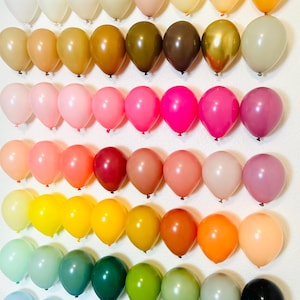 Puede incluir: Una pared decorada con filas de globos coloridos en varios tonos de rosa, rojo, naranja, amarillo, verde, azul y morado. Los globos est&aacute;n dispuestos en un patr&oacute;n de arco&iacute;ris.