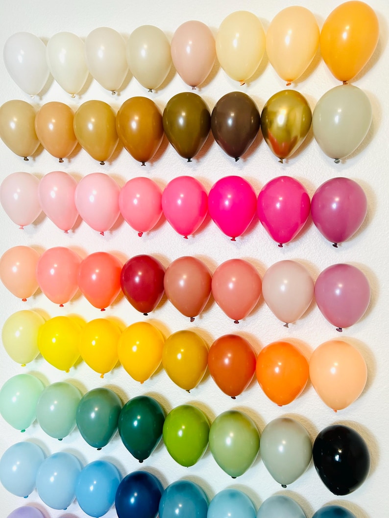 Puede incluir: Una pared decorada con filas de globos coloridos en varios tonos de rosa, rojo, naranja, amarillo, verde, azul y morado. Los globos est&aacute;n dispuestos en un patr&oacute;n de arco&iacute;ris.