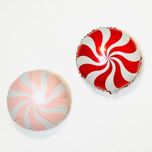 May include: Two foil balloons shaped like candy canes. One balloon is red and white, and the other is pink and white.