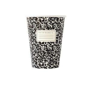 May include: A paper cup with a black and white composition notebook design. The cup has a white rim and a label that reads "THIS CUP BELONGS TO...". The cup is cylindrical and stands on a white background.