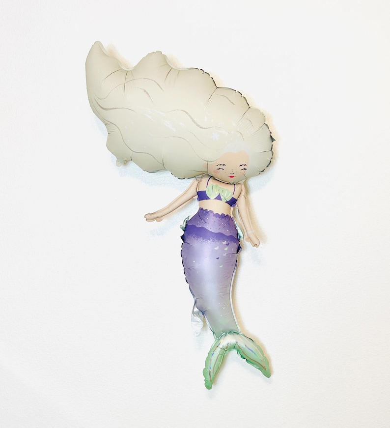 May include: A white and purple mermaid balloon with a light green tail. The mermaid has a white crown and a purple seashell bra.