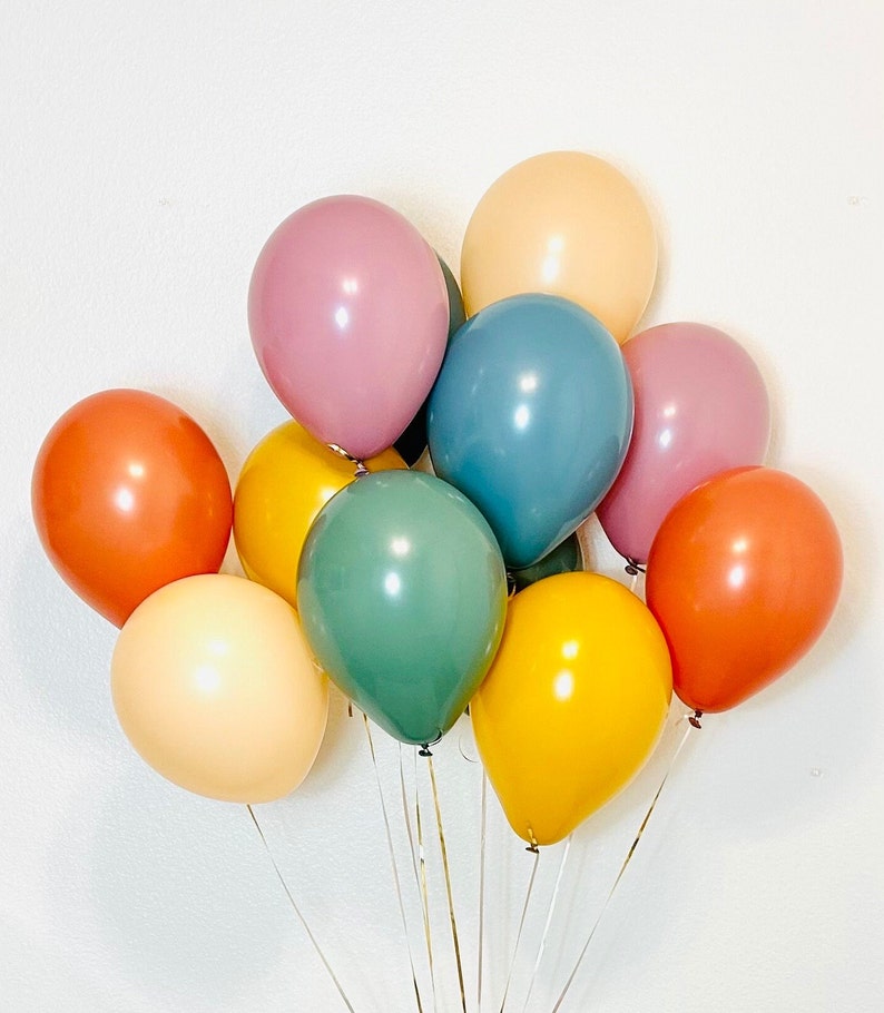 May include: A bunch of balloons in various colors including orange, yellow, green, blue, and pink. The balloons are tied together with strings and are arranged in a cluster.