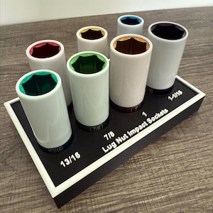 May include: A set of white lug nut impact sockets with colored interiors, arranged on a black tray with white text. The tray reads "7/8 Lug Nut Impact Sockets" and includes socket sizes 13/16 and 1-1/16.
