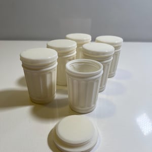 Könnte beinhalten: Sechs weiße Mini-Mülleimer mit einem einzigen Deckel. Die Mülleimer haben ein geripptes Design.