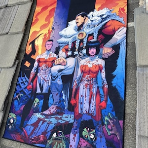 May include: A rectangular comic book-style tapestry featuring three figures in the center, with a man in a fur-lined cape. The figures are surrounded by a fiery background and a scene of zombies and blood. The color palette includes red, blue, and orange.