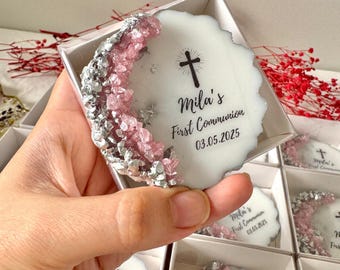 May include: White favor box with a pink and silver resin design. The box has a white label with a cross and the text "Mila's First Communion 03.05.2025".