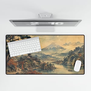 May include: A rectangular mouse mat with a Japanese landscape painting depicting a mountain, lake, and traditional buildings. A white keyboard and mouse are on the mat. The monitor above displays the numbers 2 and 16.