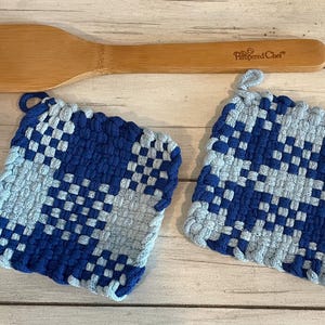 May include: Two blue and gray woven pot holders with a wooden spoon with the text "Pampered Chef" on it.