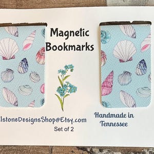 May include: Two magnetic bookmarks with a light blue background and a seashell pattern. The text "Magnetic Bookmarks" is displayed. The text "Handmade in Tennessee" and "Set of 2" are also visible.