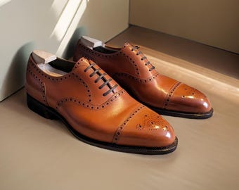 Zapatos Oxford de piel hechos a mano con puntera reforzada y suela de cuero marrón.