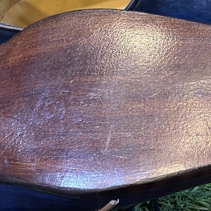 May include: Close-up of the sole of a dark brown leather shoe. The sole is worn and shows signs of use. The shoe is part of a collection of blue leather shoes, with a glimpse of the upper visible.